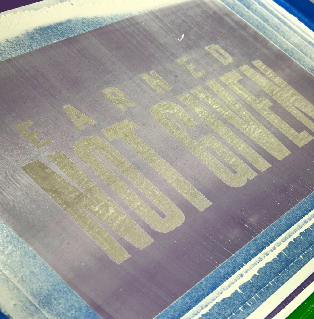 Exposed silk-screen stencil with the distressed Earned Not Given design used to hand-print Warriors Dawn shirts.