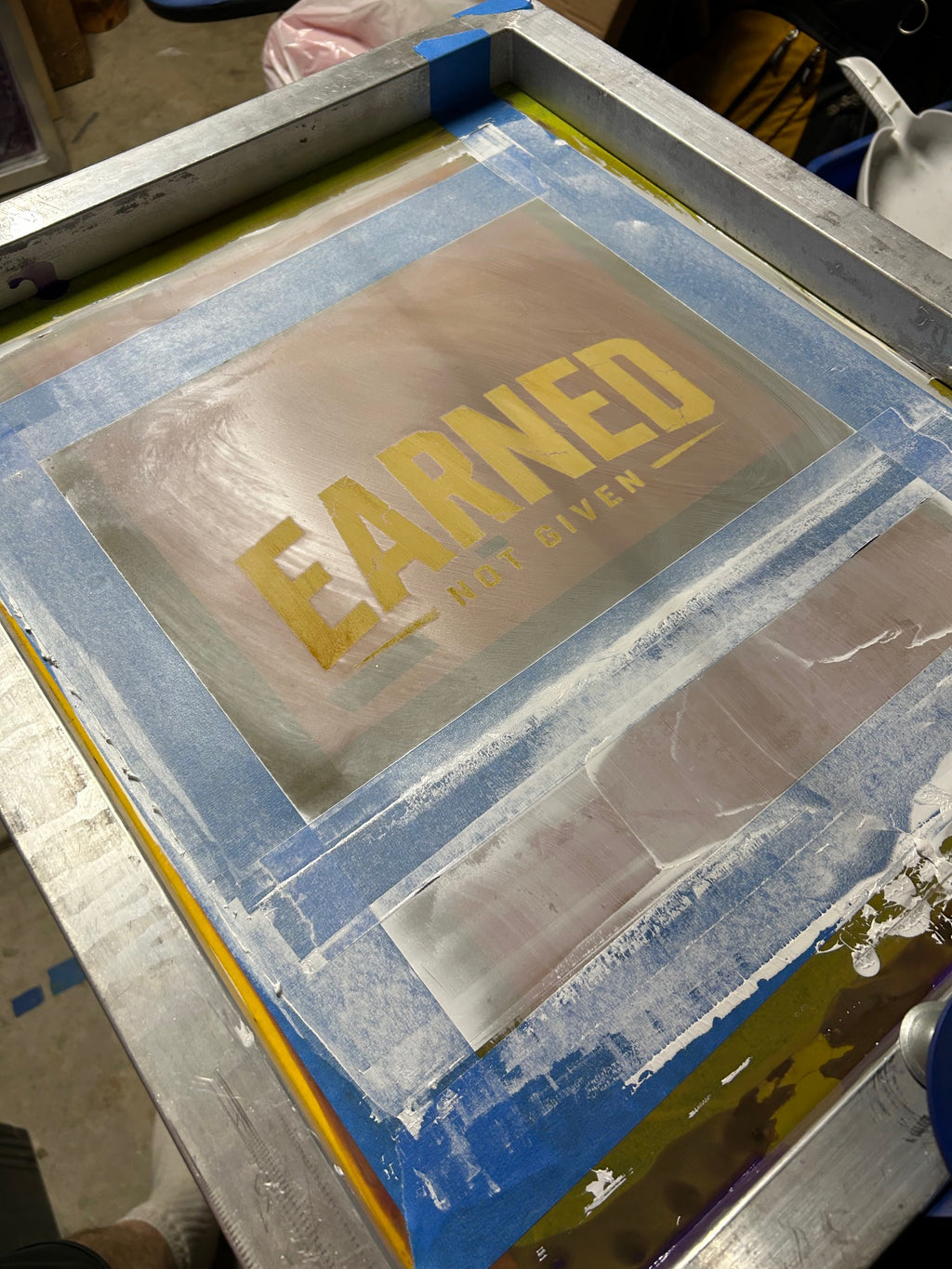 Exposed silk-screen stencil with the distressed Earned Not Given design used to hand-print Warriors Dawn shirts.